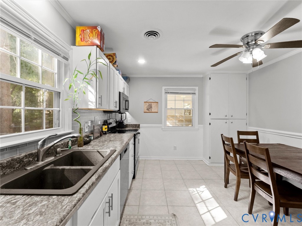 Kitchen featuring white cabinetry, stone-finish countertops, subway tile backsplash, ceramic tile flooring, and integrated ceiling fan with lighting