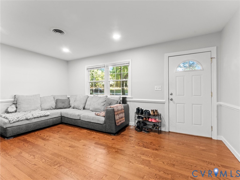 Hardwood flooring, neutral wall paint, white trim with chair rail molding, dual-pane windows, and a white six-panel exterior door with a semi-circular transom window