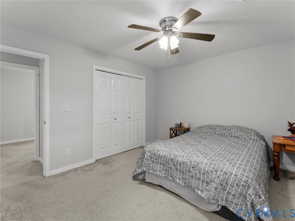 Neutral-toned carpeting, white bi-fold closet doors, and a ceiling fan with integrated multi-bulb lighting
