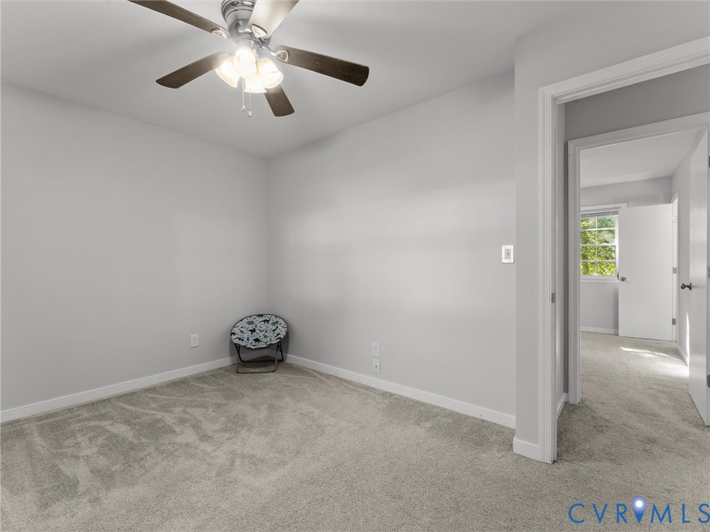 Neutral-toned wall paint, plush carpeting, ceiling fan with integrated lighting, and white interior door frames
