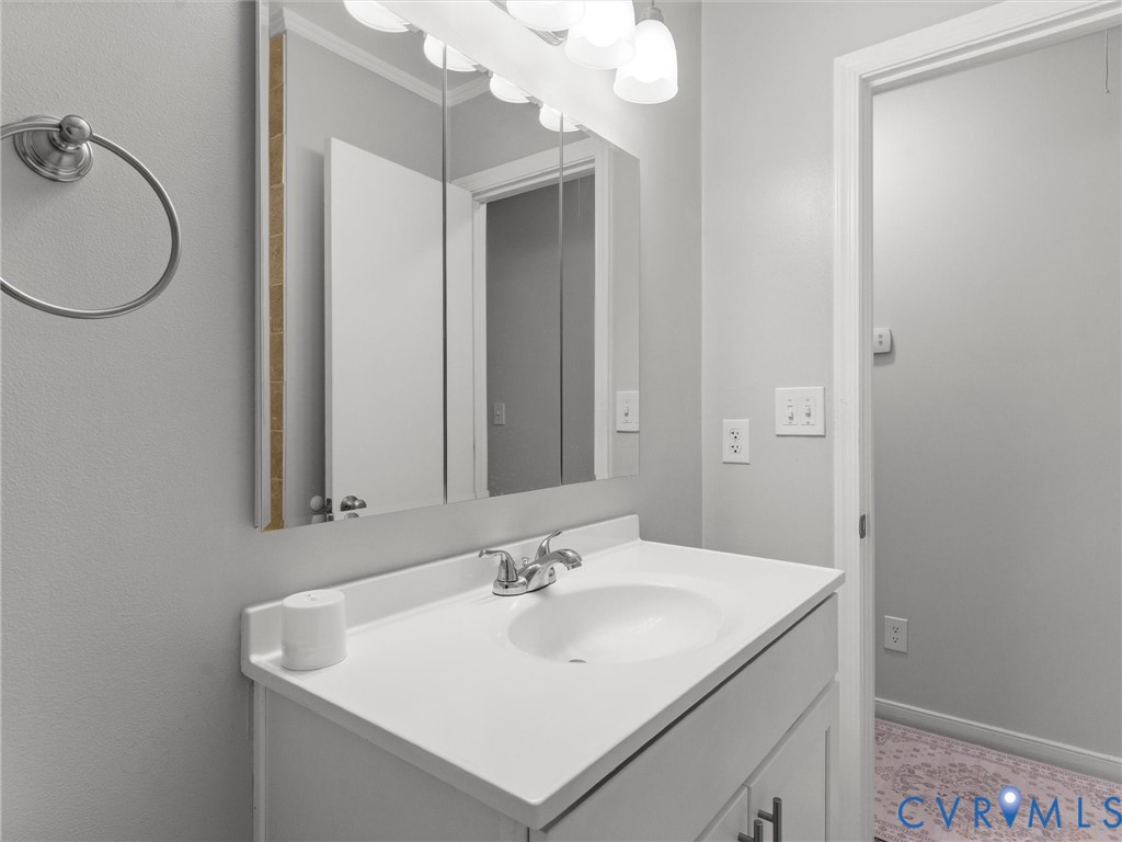 Vanity with an integrated sink and countertop, triple-panel mirrored medicine cabinet, and five-light vanity fixture