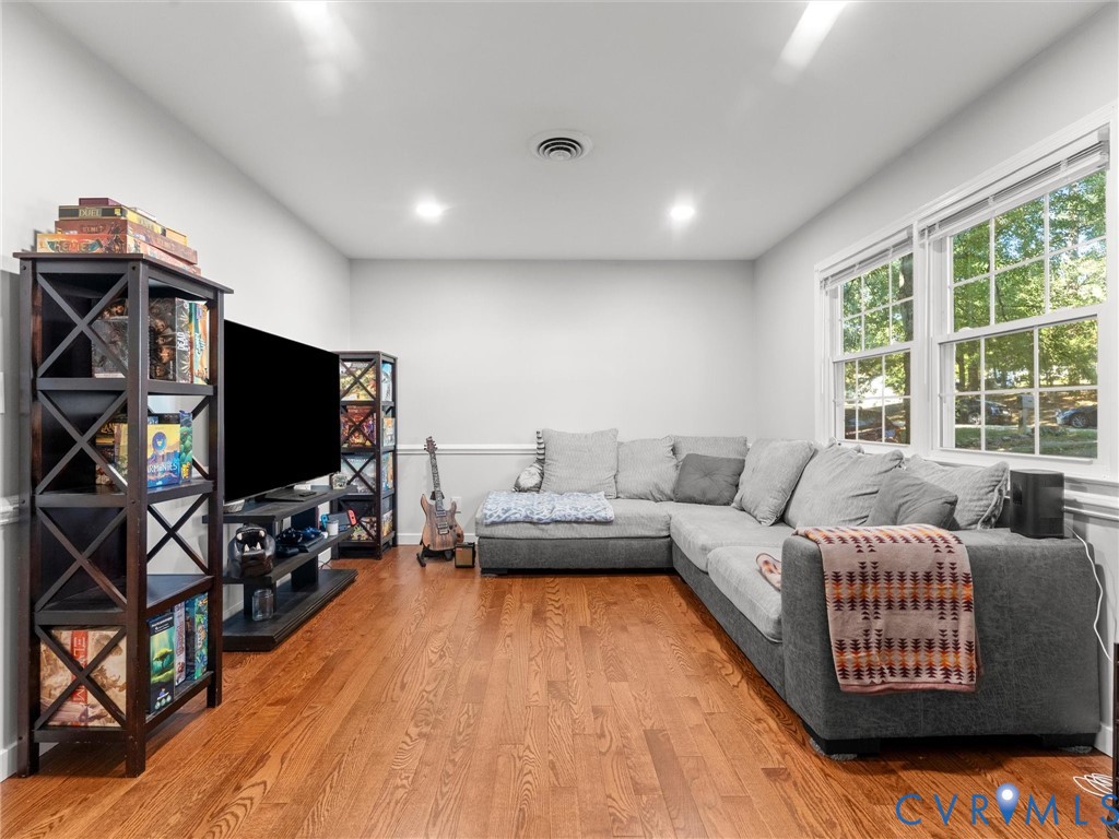 Living area featuring wood-finish flooring, recessed lighting, chair rail molding, and multi-pane windows