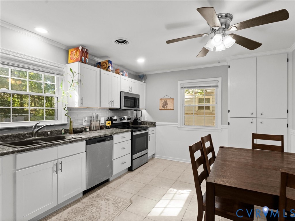 Kitchen featuring white cabinetry, stone-finish countertops, stainless steel appliances, tile flooring, and a ceiling fan with integrated lighting