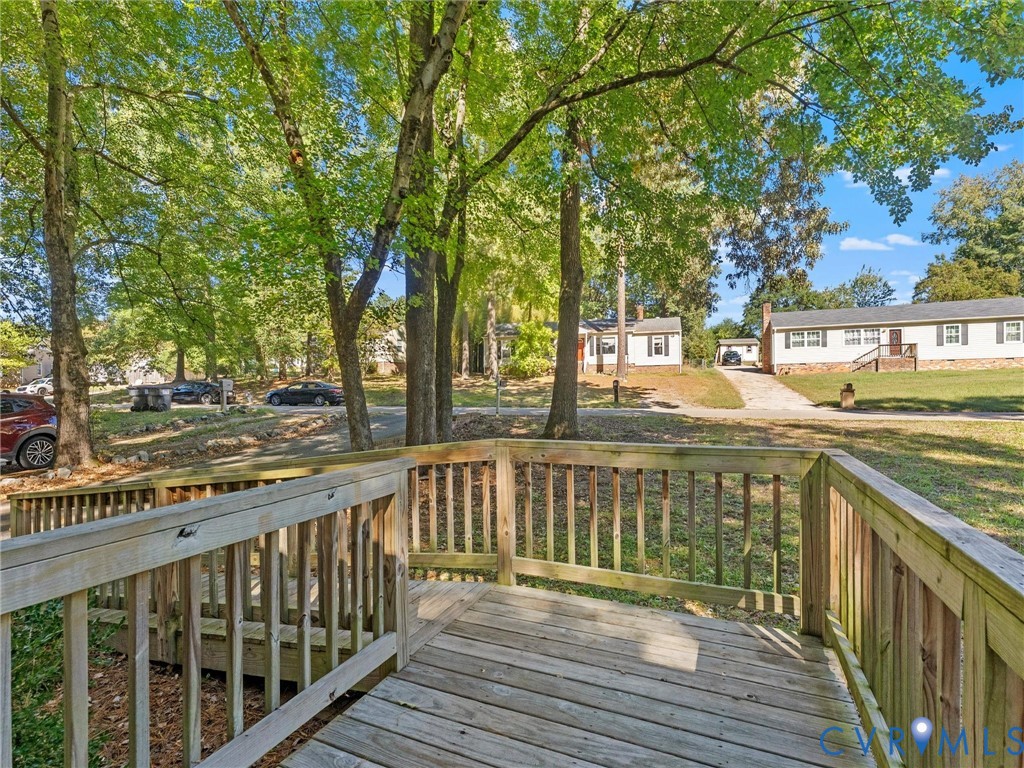 Raised wooden deck featuring wood balustrades and a multi-level design overlooking a tree-lined lot