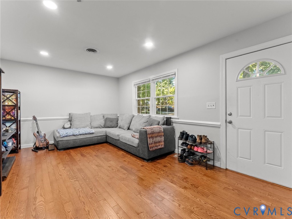 Interior space featuring wood-finish flooring, recessed lighting, chair rail molding, double-pane windows, and a solid-core entry door with an arched glass insert