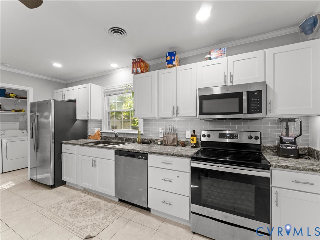 Kitchen featuring white cabinetry, stone-finish countertops, stainless steel appliances, subway tile backsplash, and ceramic tile flooring