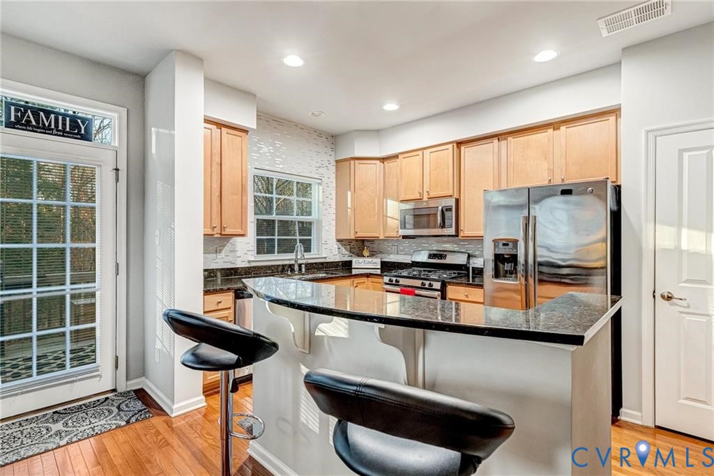 Kitchen with visible vents, light wood-style flooring, light brown cabinetry, a sink, and stainless steel appliances Kitchen with visible vents, light wood-style flooring, light brown cabinetry, a sink, and stainless steel appliances