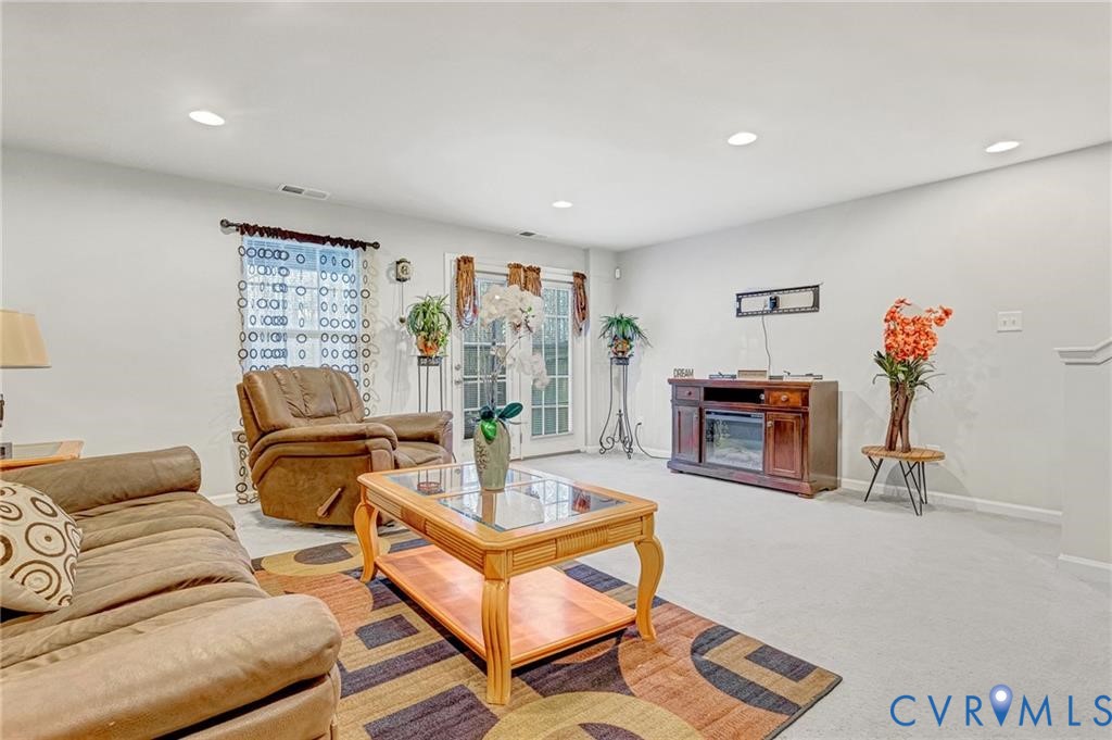 Living room featuring light carpet, recessed lighting, visible vents, and baseboards
