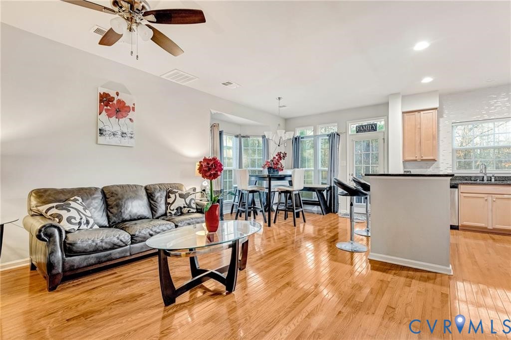 Living room featuring light wood-style flooring, visible vents, and ceiling fan Living room featuring light wood-style flooring, visible vents, and ceiling fan