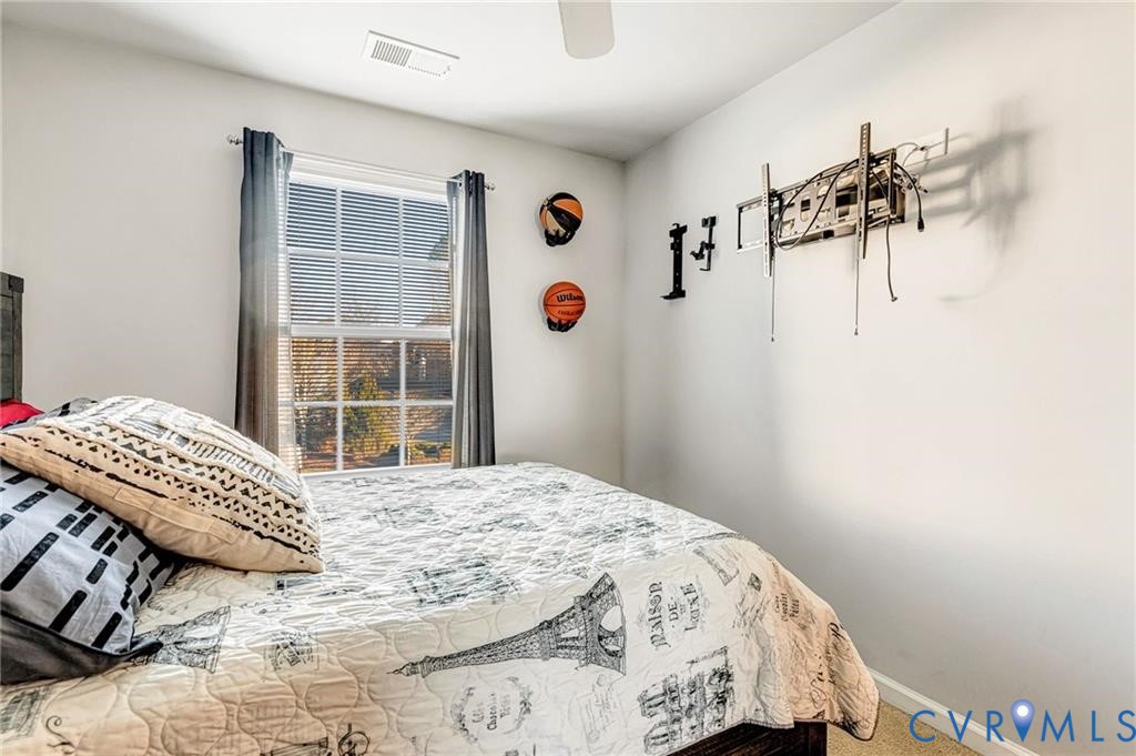 Carpeted bedroom with visible vents, baseboards, and ceiling fan