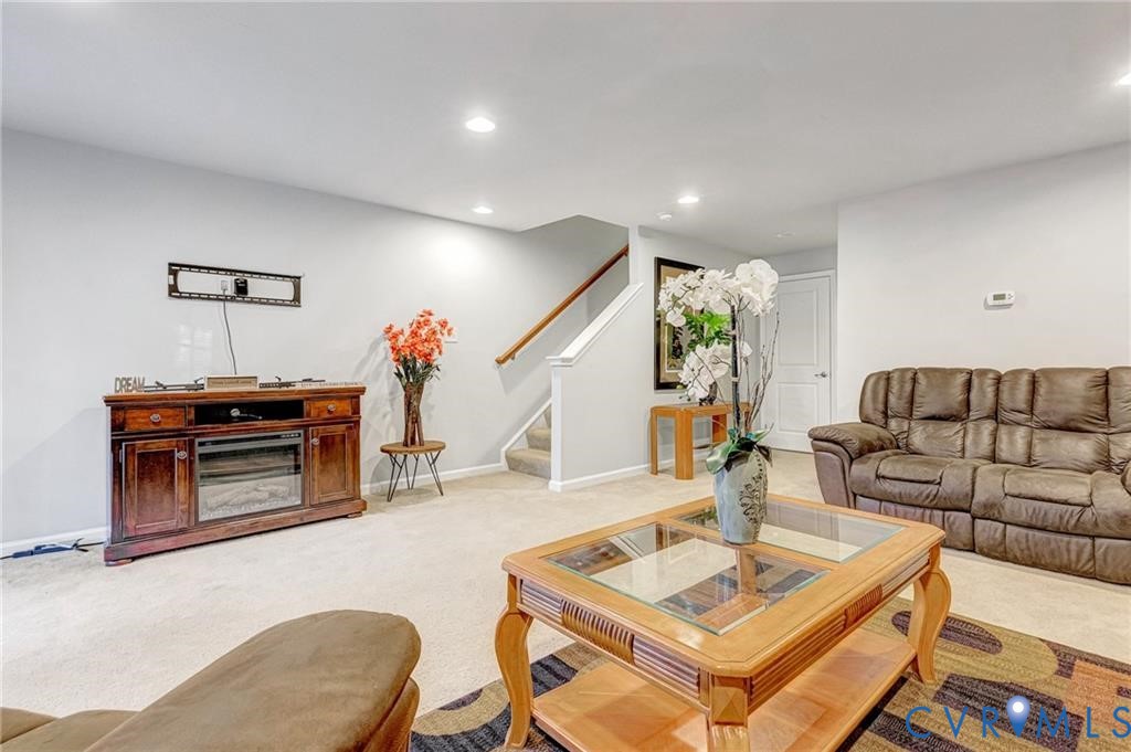 Living area featuring stairway, recessed lighting, light colored carpet, and baseboards