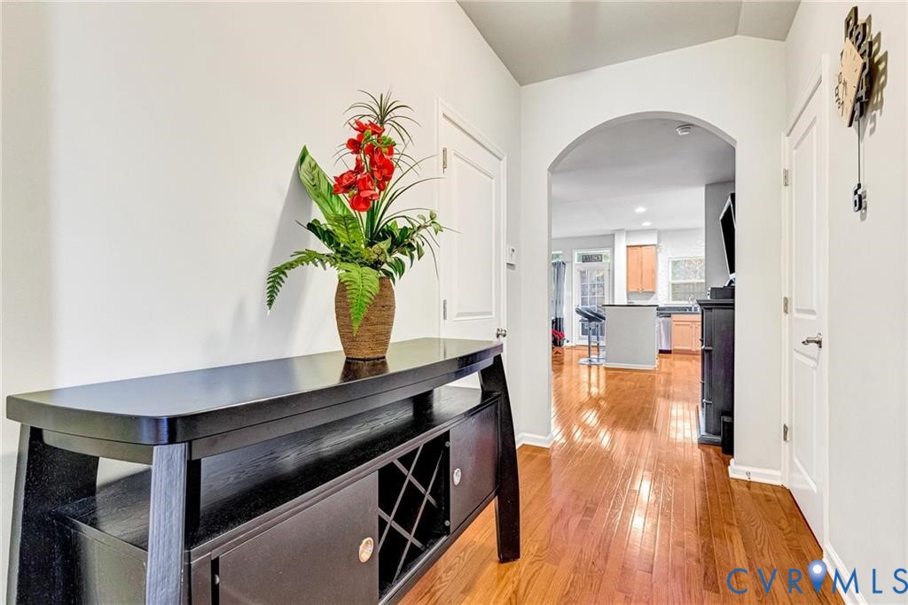 Corridor featuring light wood-style floors, arched walkways, and baseboards Corridor featuring light wood-style floors, arched walkways, and baseboards