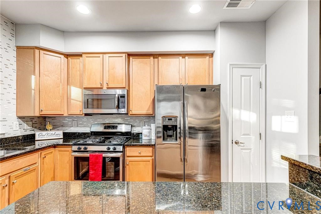 Kitchen featuring visible vents, dark stone countertops, recessed lighting, appliances with stainless steel finishes, and decorative backsplash