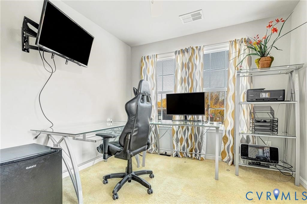 Carpeted home office with visible vents and baseboards