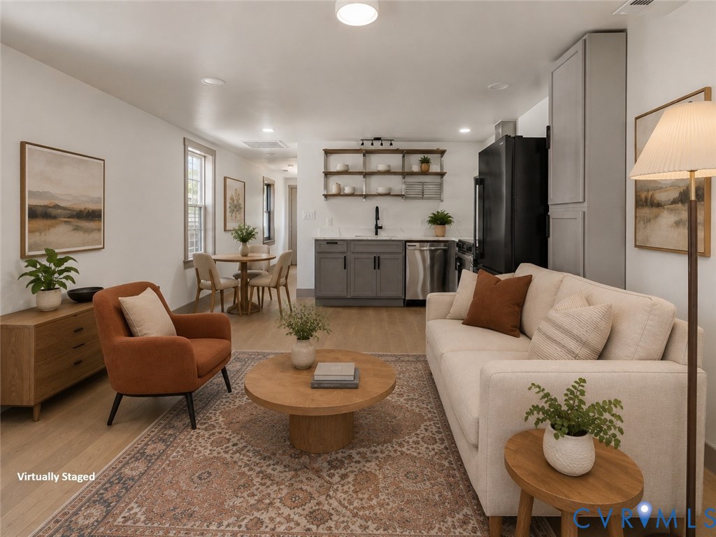 Open concept space featuring wood-finish flooring, charcoal cabinetry, stainless steel appliances, and wall-mounted open shelving