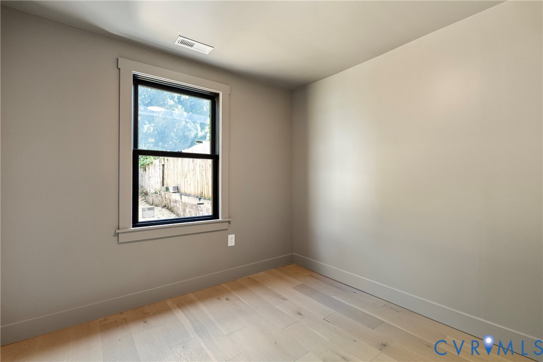 Neutral-toned walls paired with light wood-finish flooring and a single-hung window featuring a dark frame