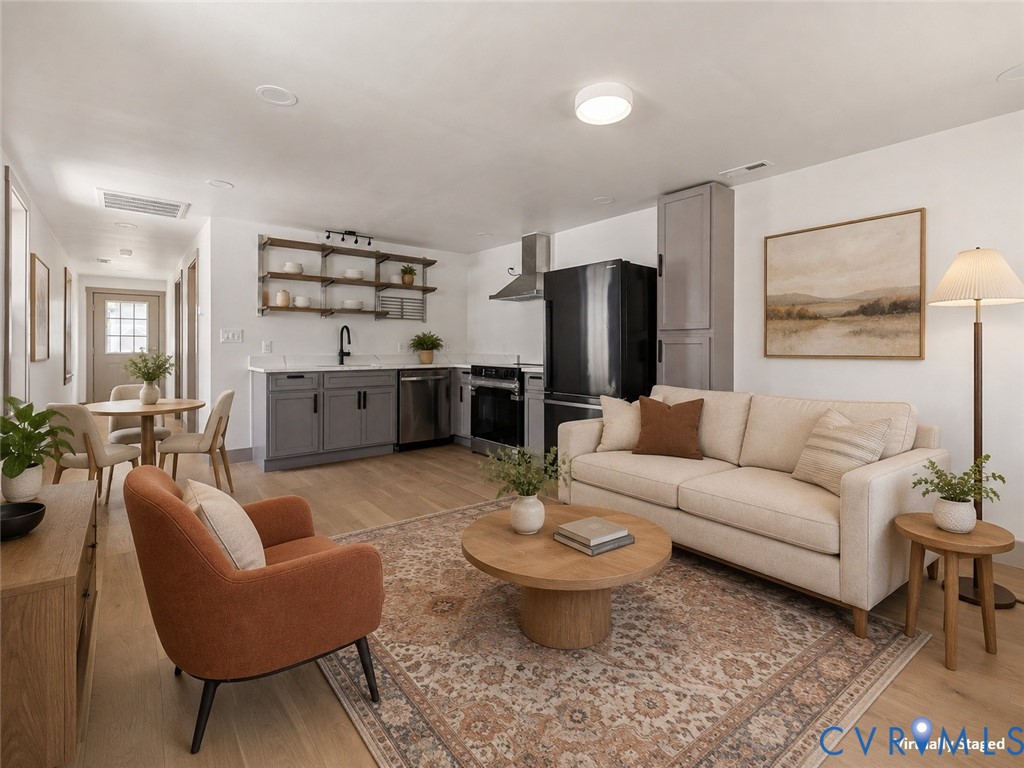 Kitchen featuring gray cabinetry, wood-finish flooring, open wall shelving, stainless steel appliances, and a range hood