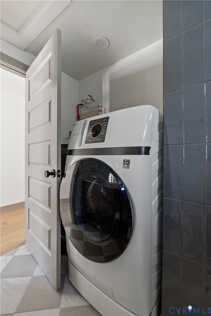 Utility area featuring geometric tile flooring, vertical dark-toned wall tiling, and a white five-panel interior door with matte black hardware