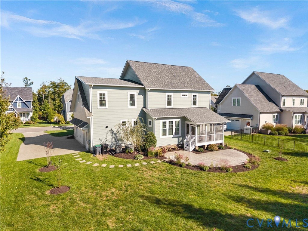 Two-story residence featuring light-toned lap siding, a rear covered porch, a curved concrete patio, and an expansive lawn