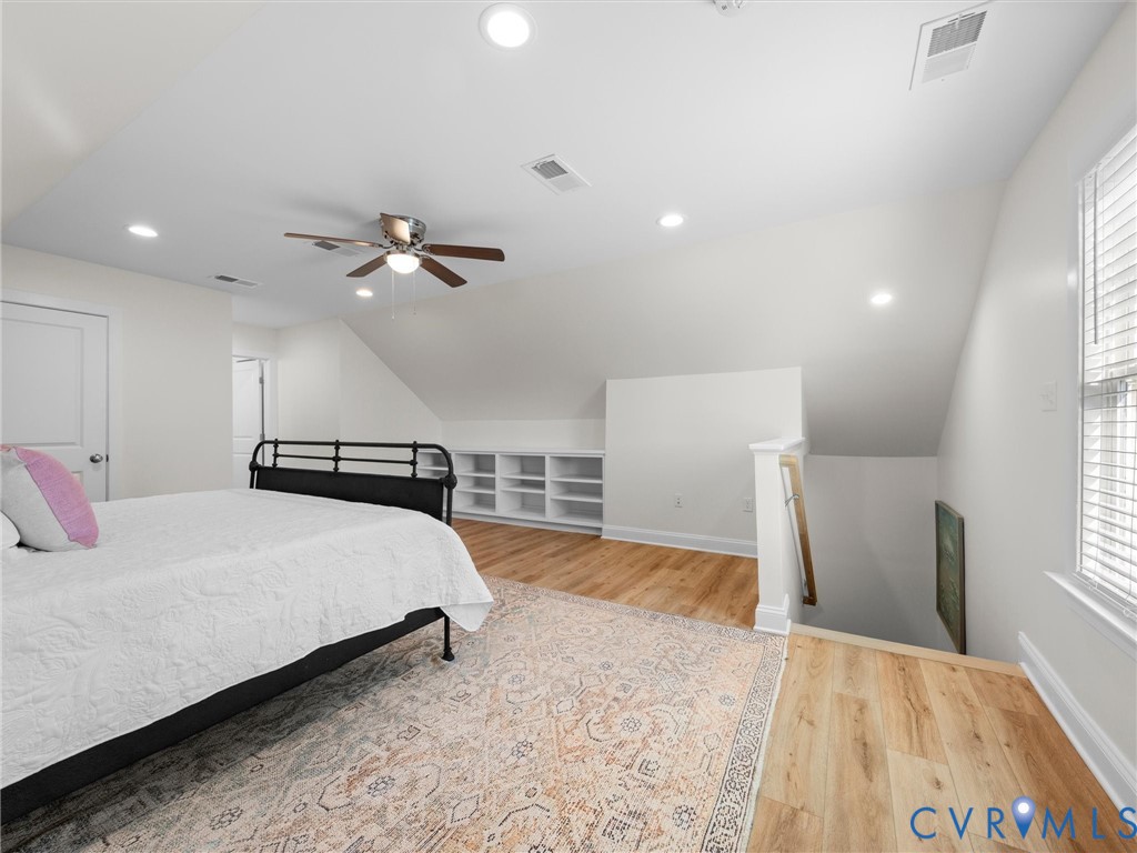 Wood-finish flooring, vaulted ceilings, recessed lighting, ceiling fan, and built-in shelving