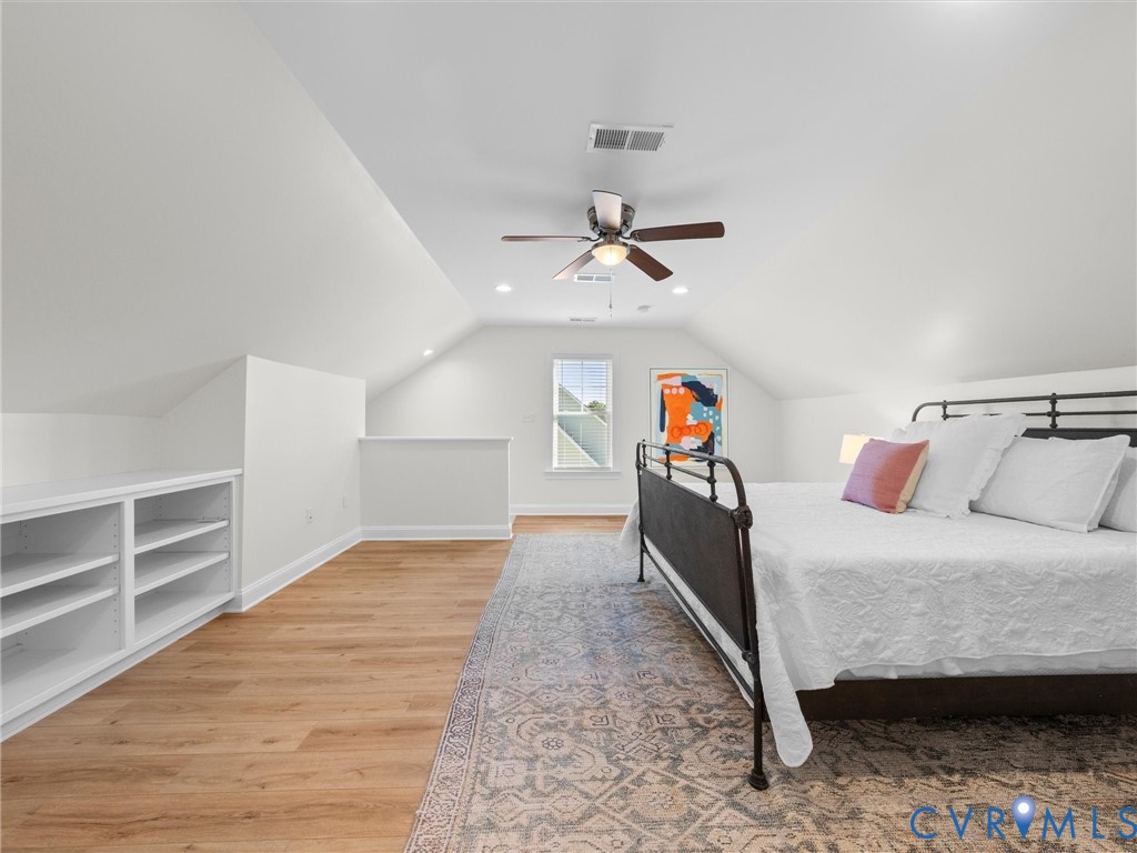 Vaulted ceilings, wood-finish flooring, built-in white shelving, recessed lighting, and a centrally mounted ceiling fan