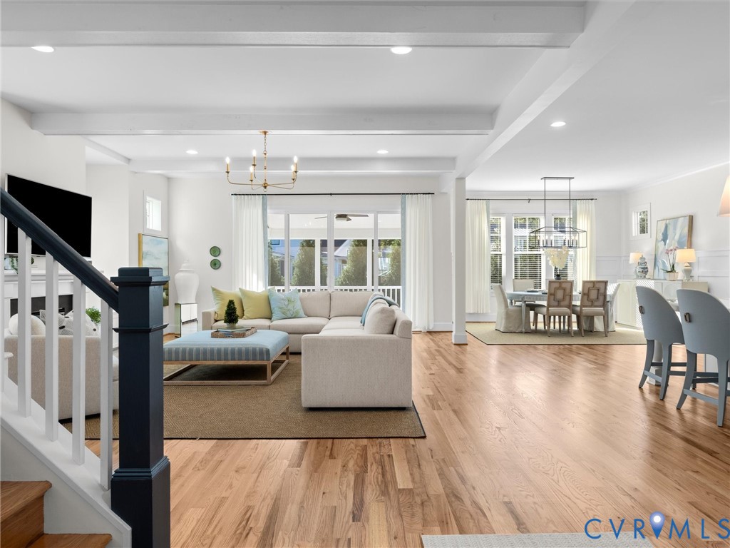 Open-concept interior featuring wood-finish flooring, exposed ceiling beams, recessed lighting, and a large sliding glass door with a transom window