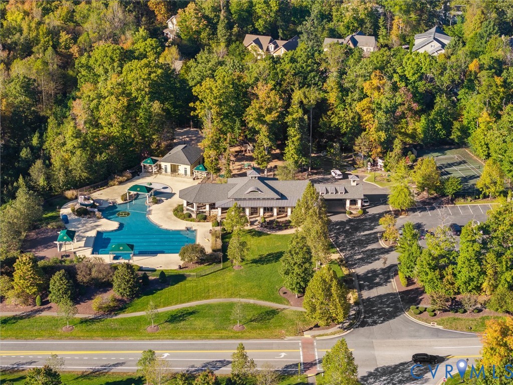 Community facility featuring an outdoor swimming pool, tennis court, sprawling lawn, and paved parking area