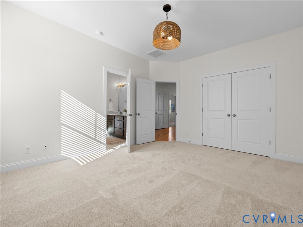 Neutral-toned carpeting, textured drum pendant lighting, double-door closet with paneled detailing, and interior solid-core doors