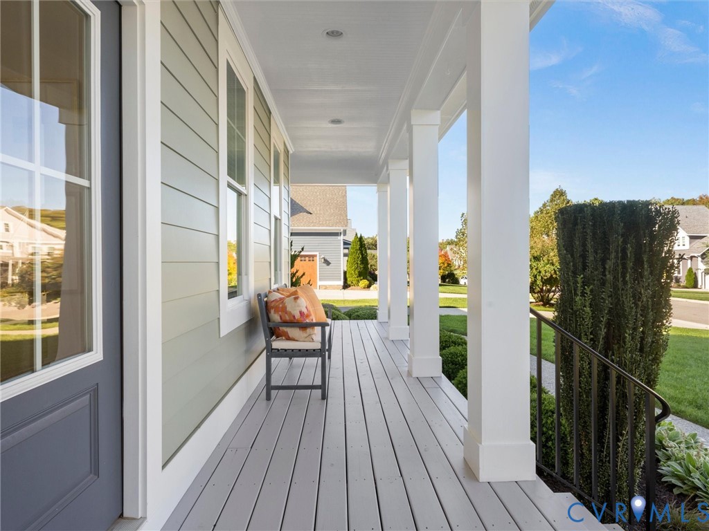 Covered front porch featuring light grey horizontal lap siding, square structural columns, painted wooden decking, and a metal handrail Covered front porch featuring light grey horizontal lap siding, square structural columns, painted wooden decking, and a metal handrail