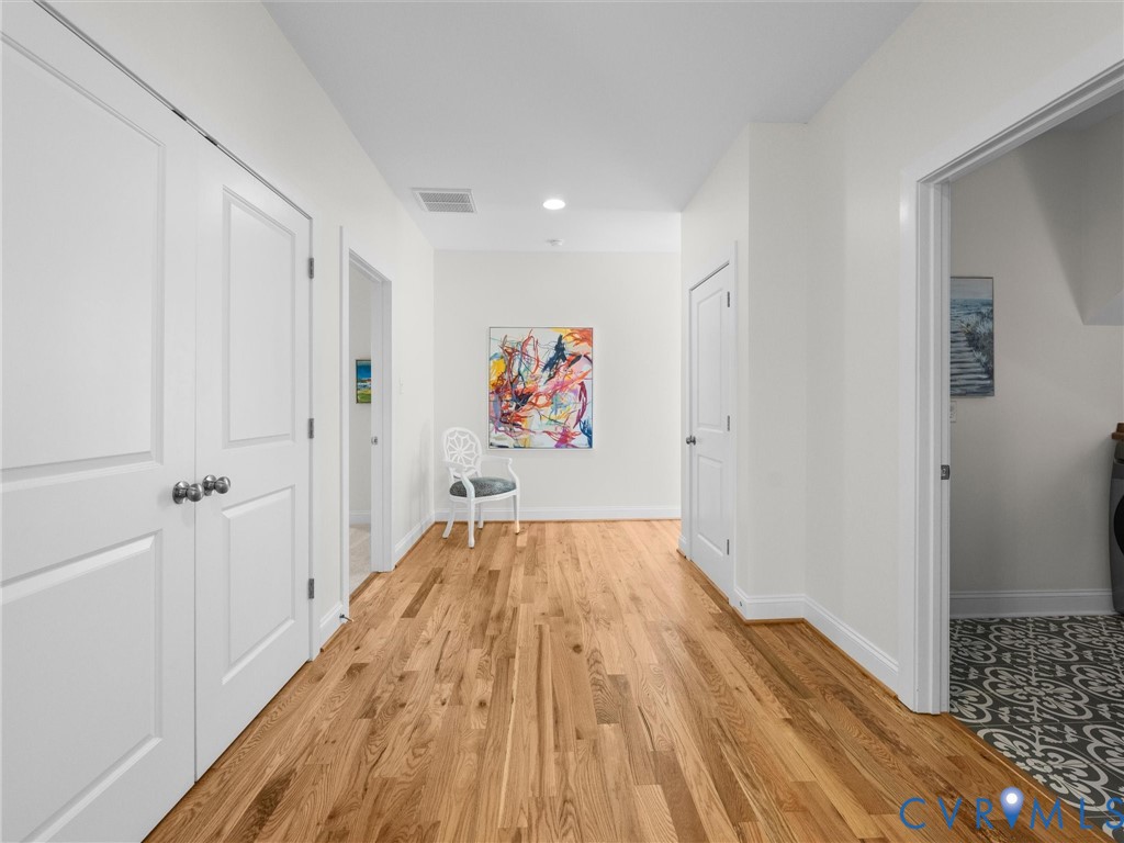 Interior hallway featuring wood-finish flooring, two-panel interior doors, recessed lighting, and patterned floor tile