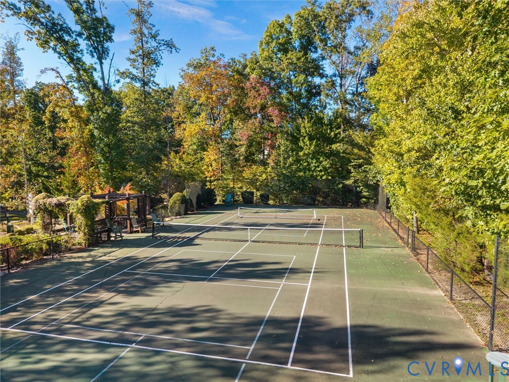 Tennis court featuring a hard surface, perimeter fencing, and a wooden pergola structure
