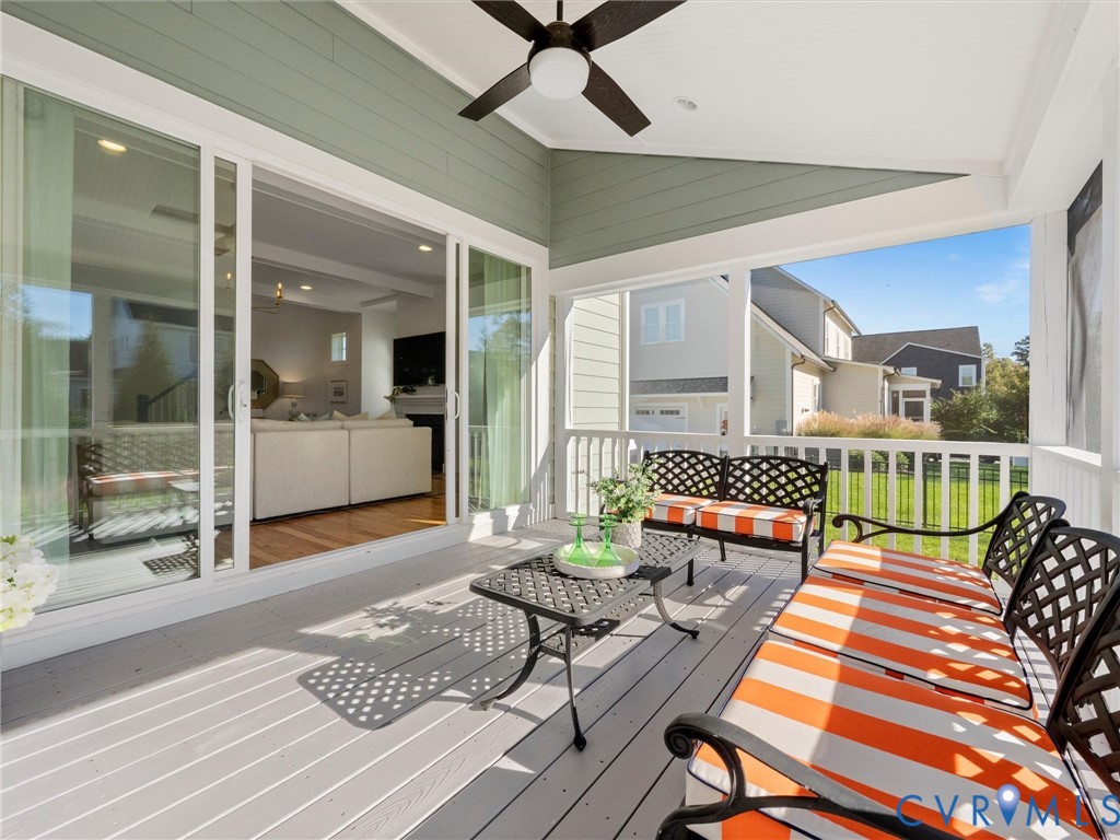 Screened-in porch featuring gray composite decking, horizontal siding, white balustrades, and a ceiling-mounted light fixture with a fan