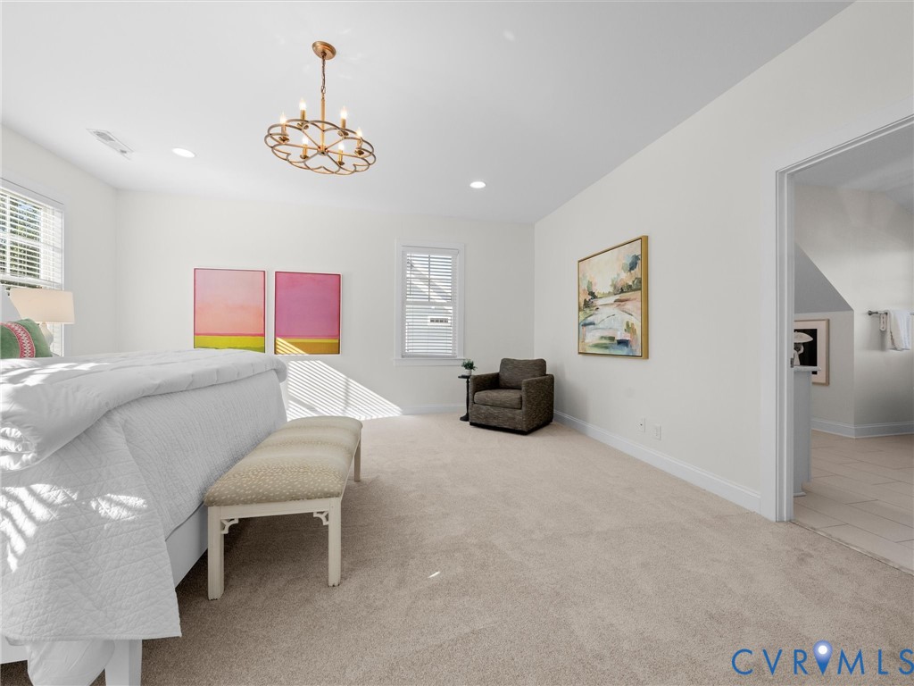 Neutral-toned carpeting, multi-light metal chandelier, and windows with integrated blinds