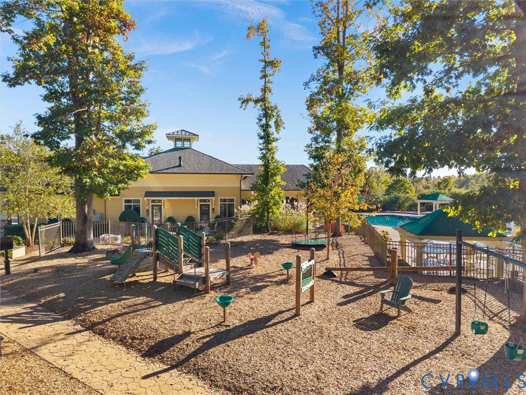 Recreational area featuring a playground with integrated play structures, wood mulch surfacing, fenced outdoor swimming pool, and mature trees