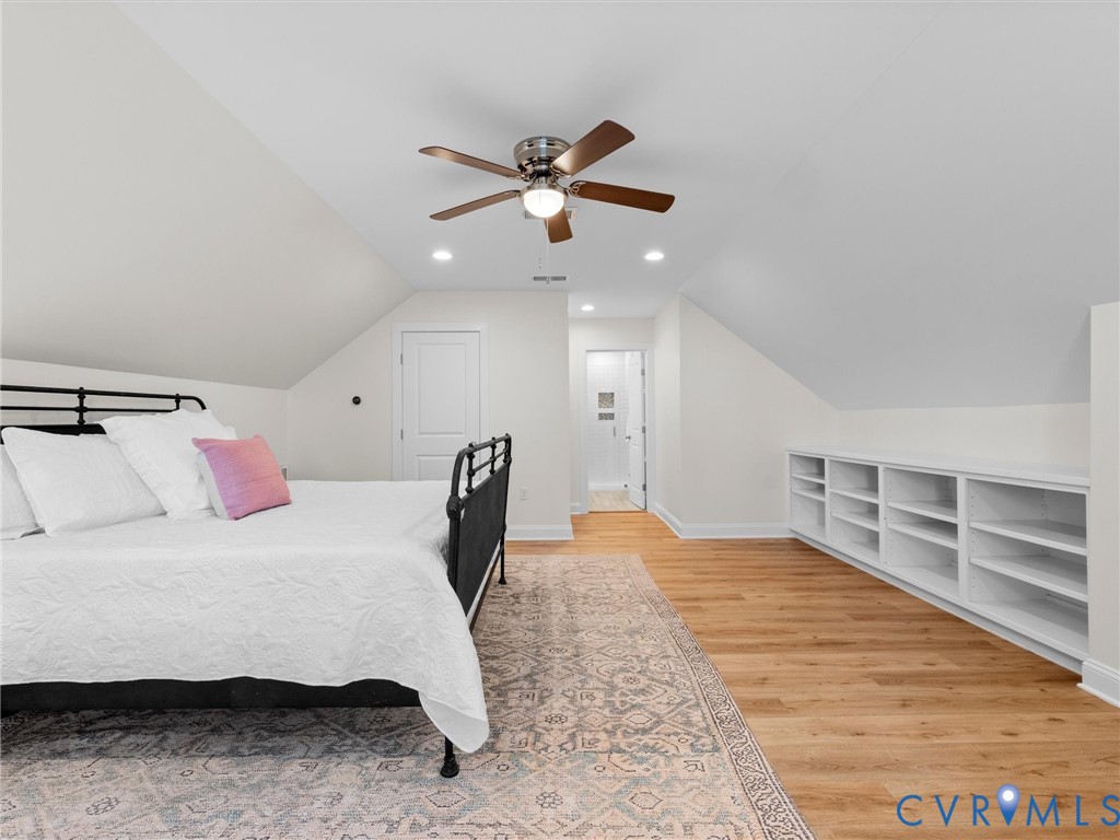Vaulted ceilings, wood-finish flooring, built-in cabinetry, and a ceiling fan with integrated lighting