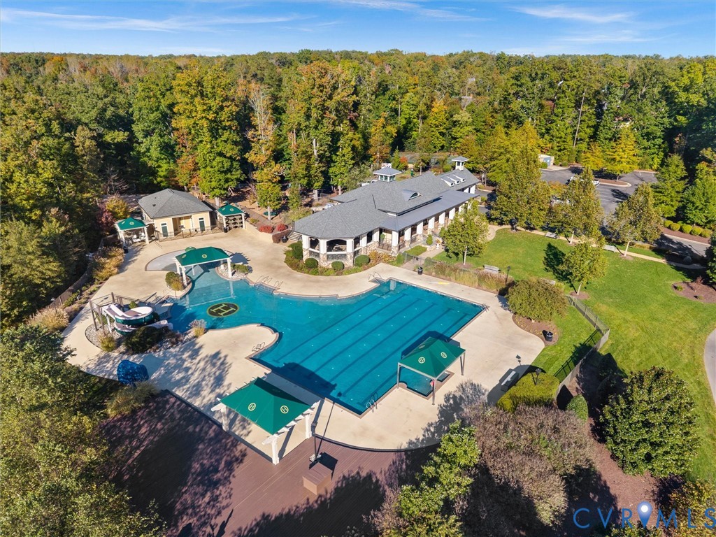 Outdoor recreation area featuring a lap-style swimming pool, integrated water slide, covered cabana structures, concrete pool deck, and landscaped grounds