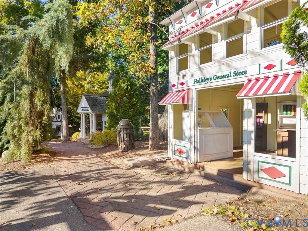 Custom-built wood play structures featuring detailed architectural siding, striped fabric awnings, multi-pane windows, and paved brick pathways