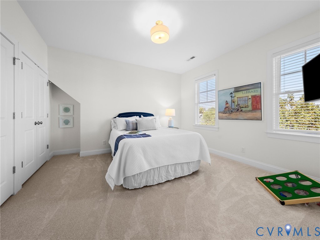 Neutral interior room featuring wall-to-wall carpeting, two double-hung windows, a recessed closet with dual doors, and a semi-flush mount ceiling light fixture