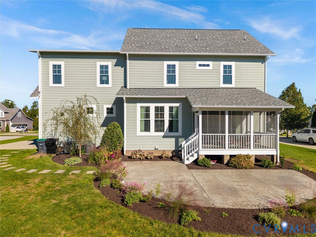 Two-story residence featuring light green horizontal siding, a screened-in porch with white railings, and a stamped concrete patio