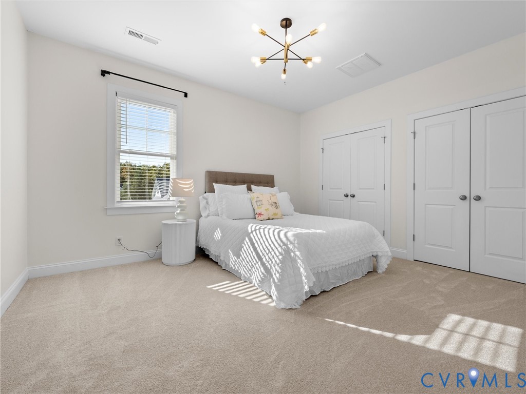 Neutral-toned carpeting, multi-pane window, modern multi-arm chandelier, and double-panel closet doors