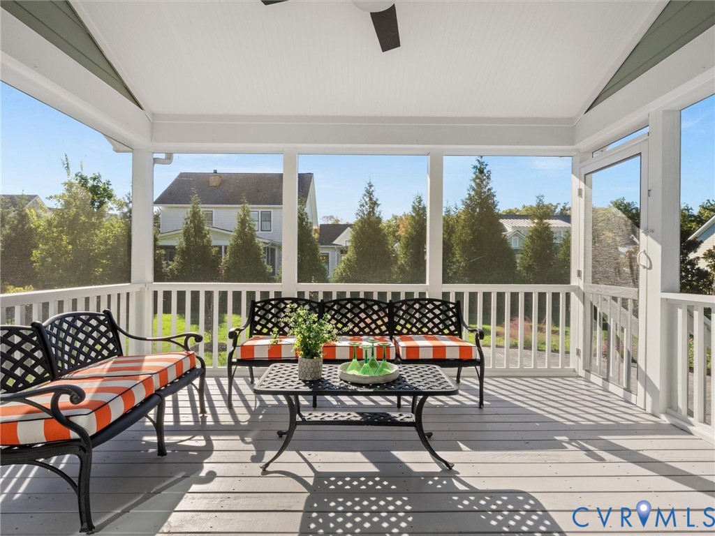 Screened-in porch featuring a vaulted ceiling, ceiling fan, and composite decking