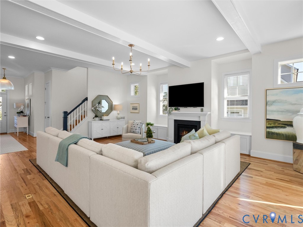 Living area featuring wood-finish flooring, recessed lighting, exposed ceiling beams, a fireplace with a mantel, and a dedicated built-in window bench
