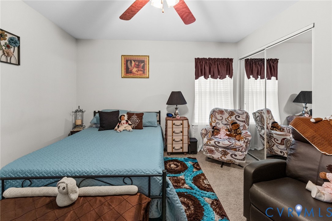 Bedroom featuring neutral wall paint, carpeted flooring, a ceiling fan, and a floor-to-ceiling mirrored sliding door closet