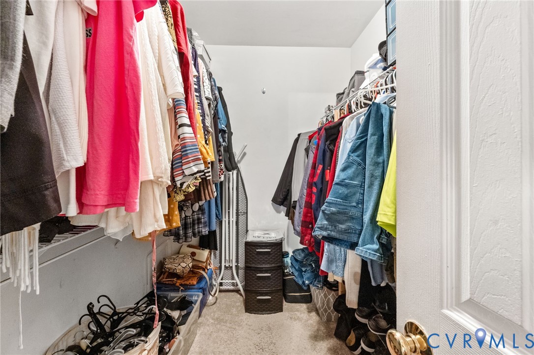 Walk-in closet featuring tiered wire shelving and neutral carpeting