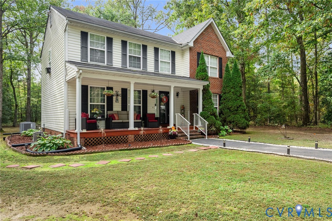 Two-story residence featuring a brick and vinyl-sided exterior, a covered front porch with lattice skirting, and a paved driveway
