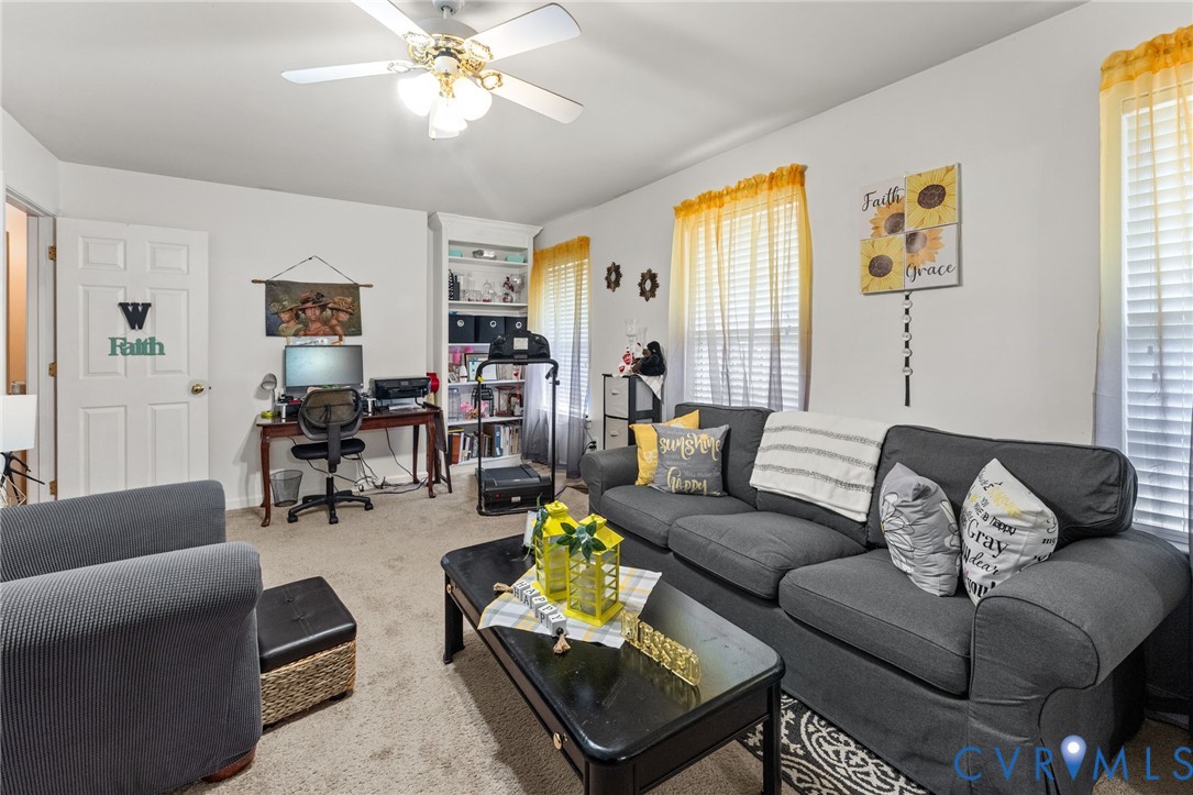 Room interior featuring wall-to-wall carpeting, built-in shelving, and a ceiling-mounted light fixture with a fan