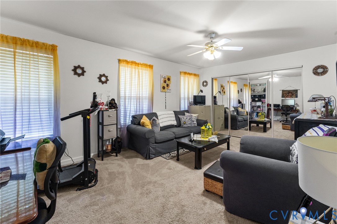 Interior space featuring wall-to-wall carpeting, ceiling fan with integrated lighting, and multi-panel floor-to-ceiling mirrored closet doors