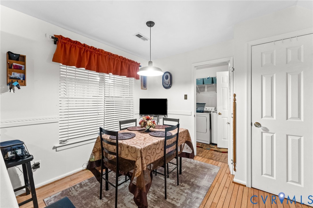Dining space featuring wood-finish flooring, chair rail molding, and a central pendant light fixture