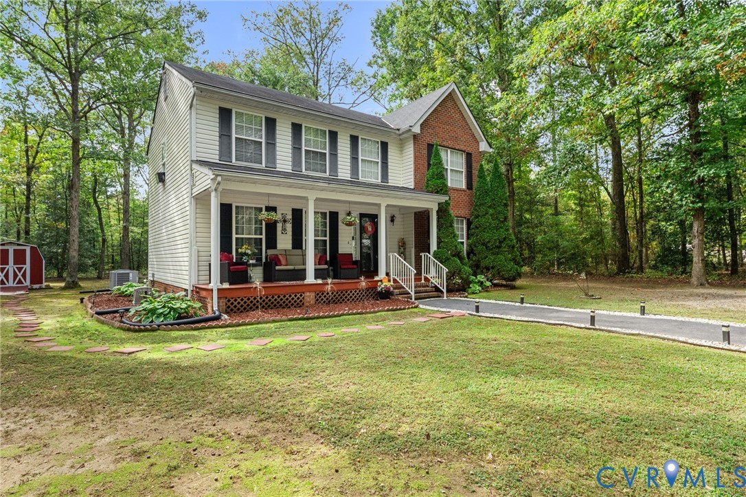 Two-story residence featuring a combination of brick and siding exterior, a covered front porch with lattice skirting, and an asphalt driveway