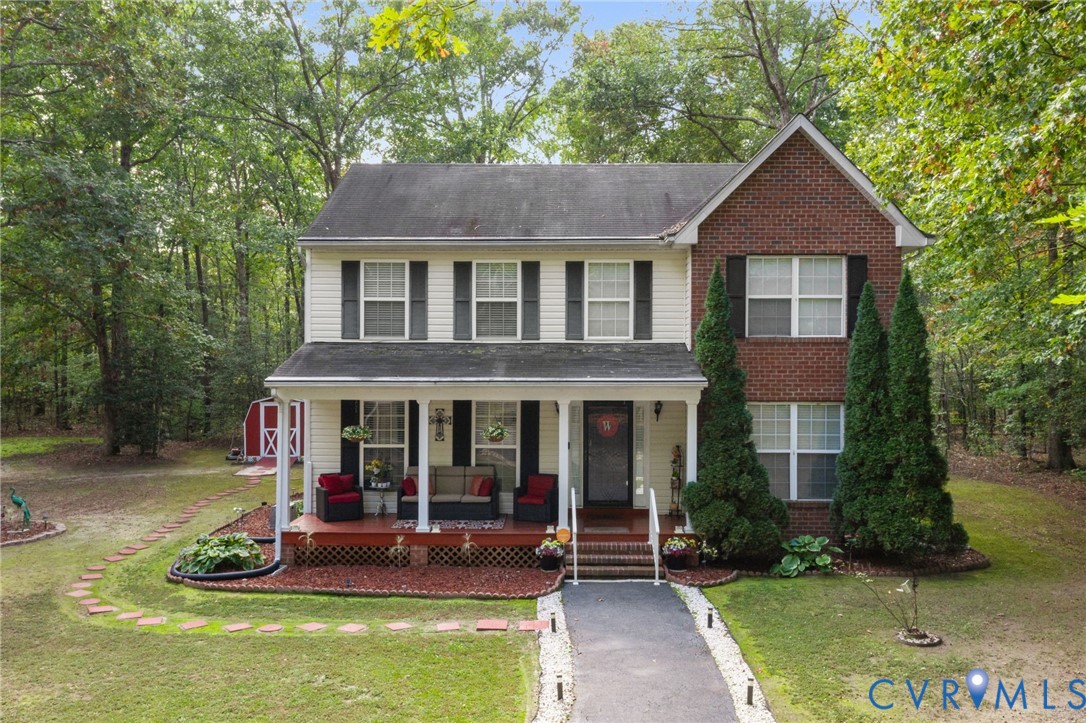 Two-story exterior featuring a partial brick faade, light-toned siding, covered front porch, and a dedicated storage shed Two-story exterior featuring a partial brick faade, light-toned siding, covered front porch, and a dedicated storage shed